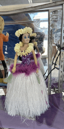 a doll wearing a purple and white dress with feathers on it