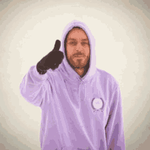 a man in a purple hoodie gives a thumbs up