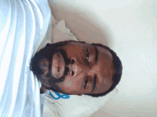 a man with a beard is laying on a white pillow with a blue ribbon on it