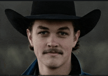 a man with a mustache wears a black cowboy hat