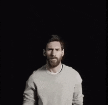 a man with a beard is wearing a grey sweater and making a face .