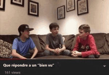 three boys are sitting on a couch talking to each other in a living room .