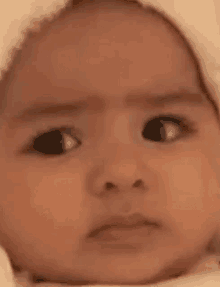 a close up of a baby 's face with a serious look on it .