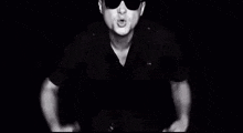 a black and white photo of a police officer wearing sunglasses and making a funny face .