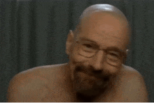 a bald man with glasses and a beard is smiling and looking at the camera .