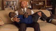 two men are sitting on a couch and one is holding the other 's waist .