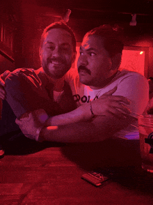 a man in a polo shirt is hugging another man in a dark room