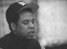 a black and white photo of a man wearing a hat that says ny on it