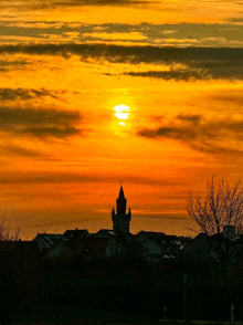 the sun is setting behind a tower in the distance