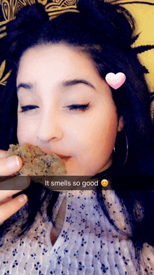 a woman eating a piece of food with a heart on her forehead that says " it smells so good "