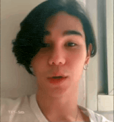 a close up of a person 's face with a white shirt and earrings .