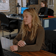 a woman sits at a desk in front of a computer with a sticker on it that says ' a '