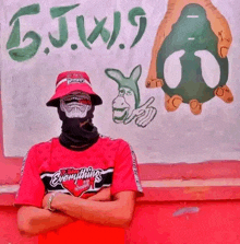 a man wearing a red shirt that says everything stands in front of a wall with graffiti on it