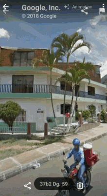 a man is riding a motorcycle down a street in front of a building that is owned by google inc.