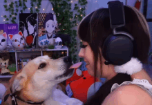 a woman wearing headphones looks at a dog licking her face in front of a sign that says live