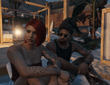 a woman with red hair sits next to a man with black tattoos