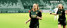 two female soccer players wearing black jerseys with super score written on them