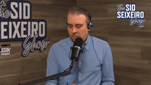 a man speaking into a microphone in front of a sign that says " the sid seixeiro show "
