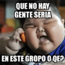 a fat baby is talking on a cell phone and making a funny face .