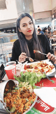 a woman sits at a table with a bucket of food and a cup of coca-cola