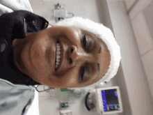 a woman wearing a bandage on her head smiles in front of a monitor that says ' ambulance ' on it