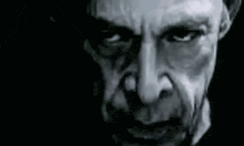 a close up of a man 's face in a black and white photo with a dark background .