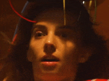 a close up of a woman 's face with a red light coming out of her head .