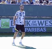 a man holding a tennis racquet on a tennis court in front of a sign that says bank of the wes