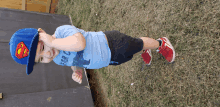 a young boy wearing a superman hat and a shirt that says ' dinosaur ' on it