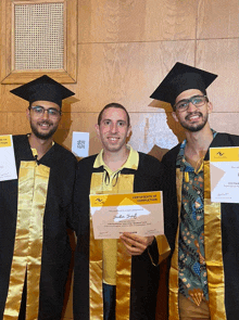 a man in a graduation cap and gown holding a certificate of completion