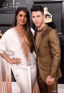 a man in a suit and a woman in a white dress pose for a picture on a red carpet .