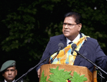 a man in a suit and tie is standing at a podium speaking into microphones