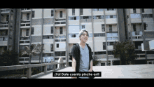 a young man stands in front of a building with the words " ya ! date cuenta pinche anti " written on the bottom