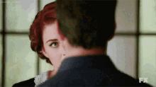 a man and a woman are looking at each other . the woman has red hair and the man has green hair .