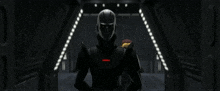 a man in a black helmet is standing in a dark hallway .