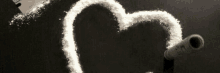 a heart is drawn on a black surface next to a dollar bill