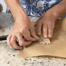 a person with a ring on their finger is holding a piece of food on a piece of brown paper