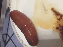 a close up of a sausage on a plate with a stain on it