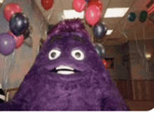 a purple stuffed animal is standing in a room with balloons .