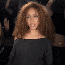 a woman in a black off the shoulder top is dancing