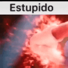 a close up of a person 's hand holding a red object with the word estupido written on it .