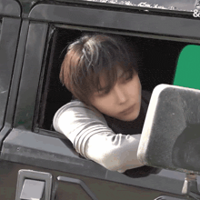 a man leaning out of the window of a car with a green screen behind him