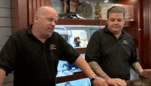 two men standing next to each other in front of a display case