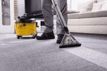 a man is using a vacuum cleaner to clean a carpet in a living room .