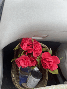 a basket of red roses sits in the trunk of a car next to a can of food