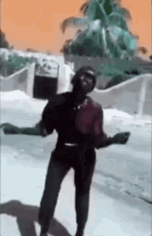 a man wearing a mask is dancing on the street .