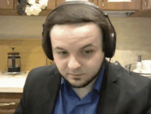 a man in a suit and blue shirt wearing headphones