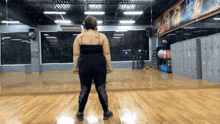 a woman stands in front of a mirror in a gym with a sign on the wall that says ' mizuno shop '