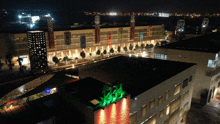 an aerial view of a city at night with a green light on the top of a building