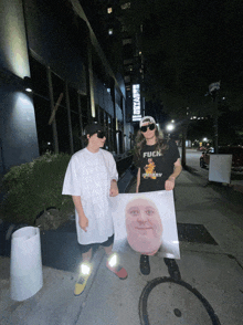 a man wearing a shirt that says fuck stands next to another man holding a poster